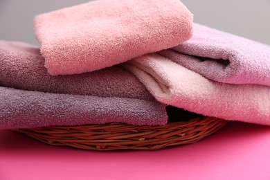 Photo of Soft towels on pink table against grey background, closeup