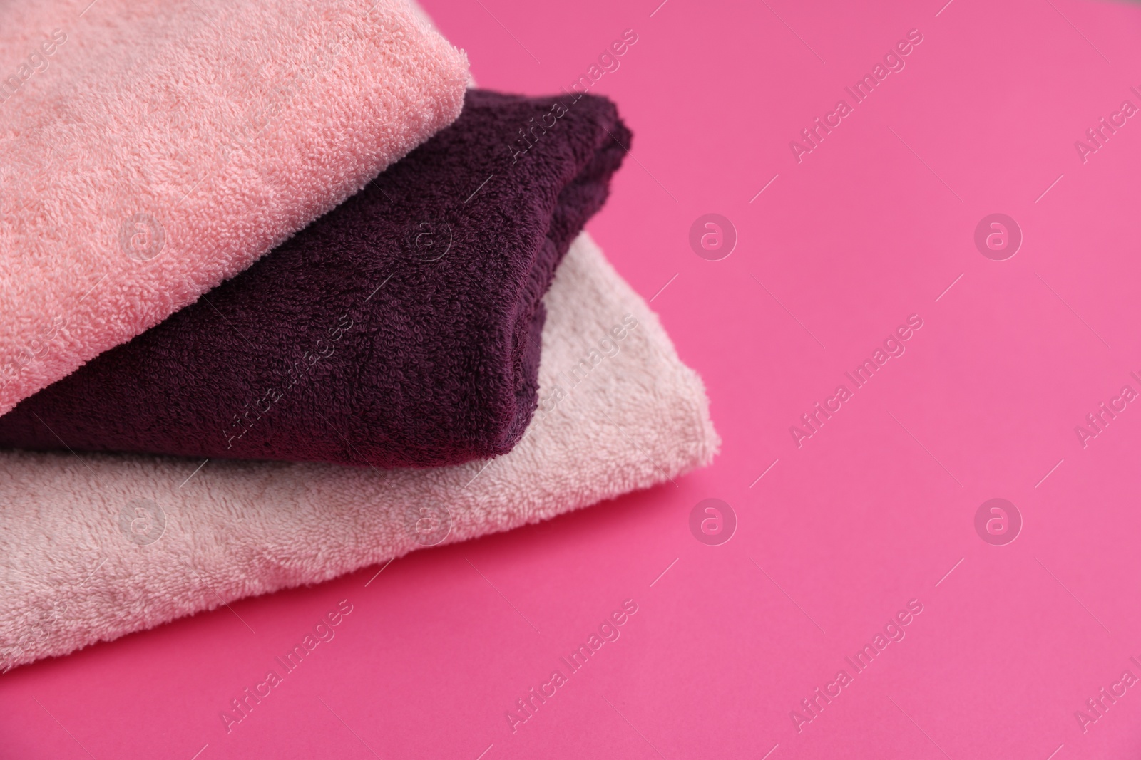 Photo of Soft towels on pink background, closeup. Space for text
