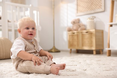 Photo of Cute newborn baby sitting on carpet in light room. Space for text