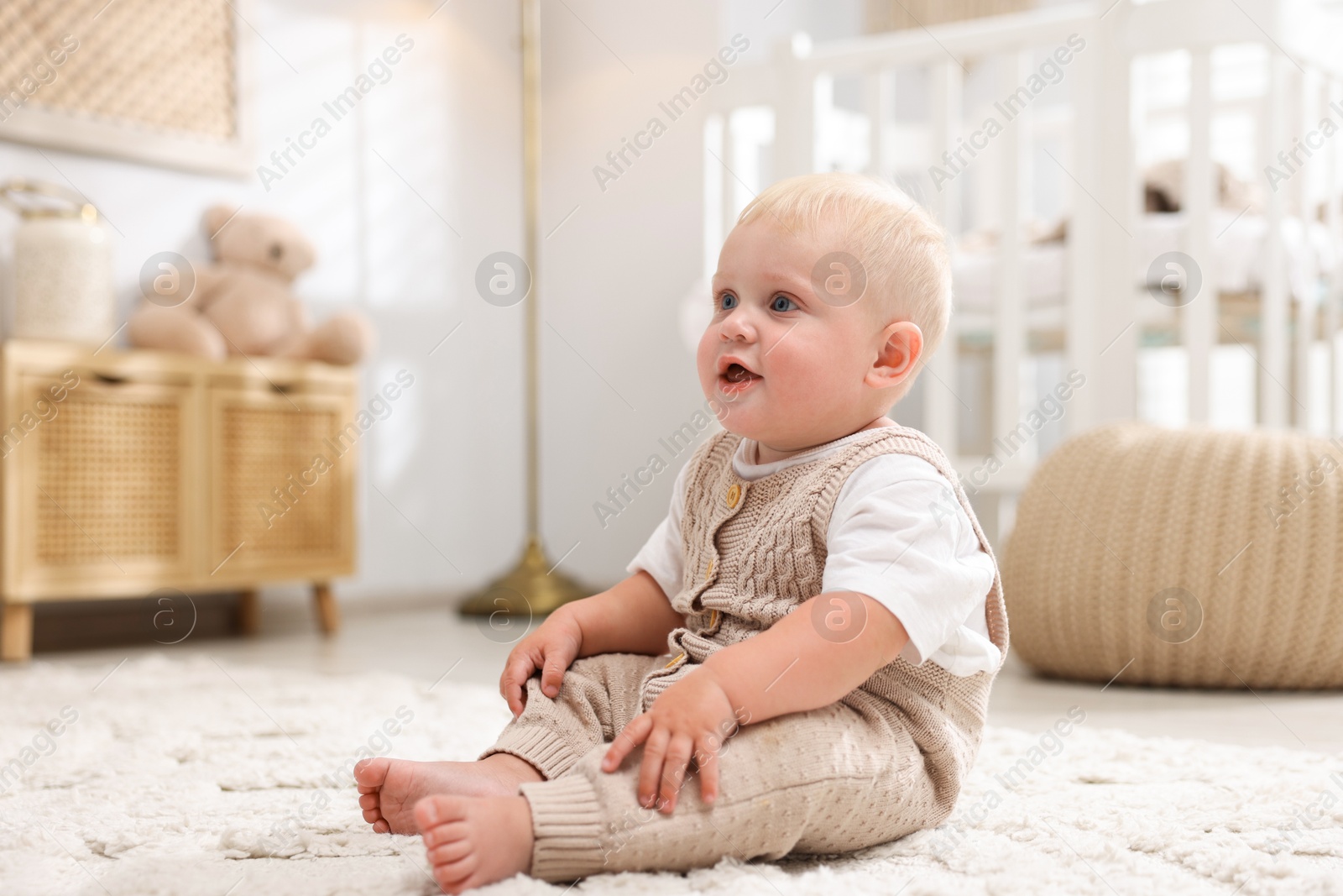 Photo of Cute newborn baby sitting on carpet in light room