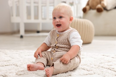 Photo of Cute newborn baby sitting on carpet in light room