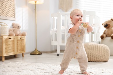 Photo of Cute newborn baby playing with toy in light room. Space for text