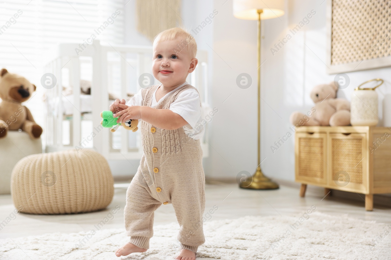 Photo of Cute newborn baby playing with toy in light room
