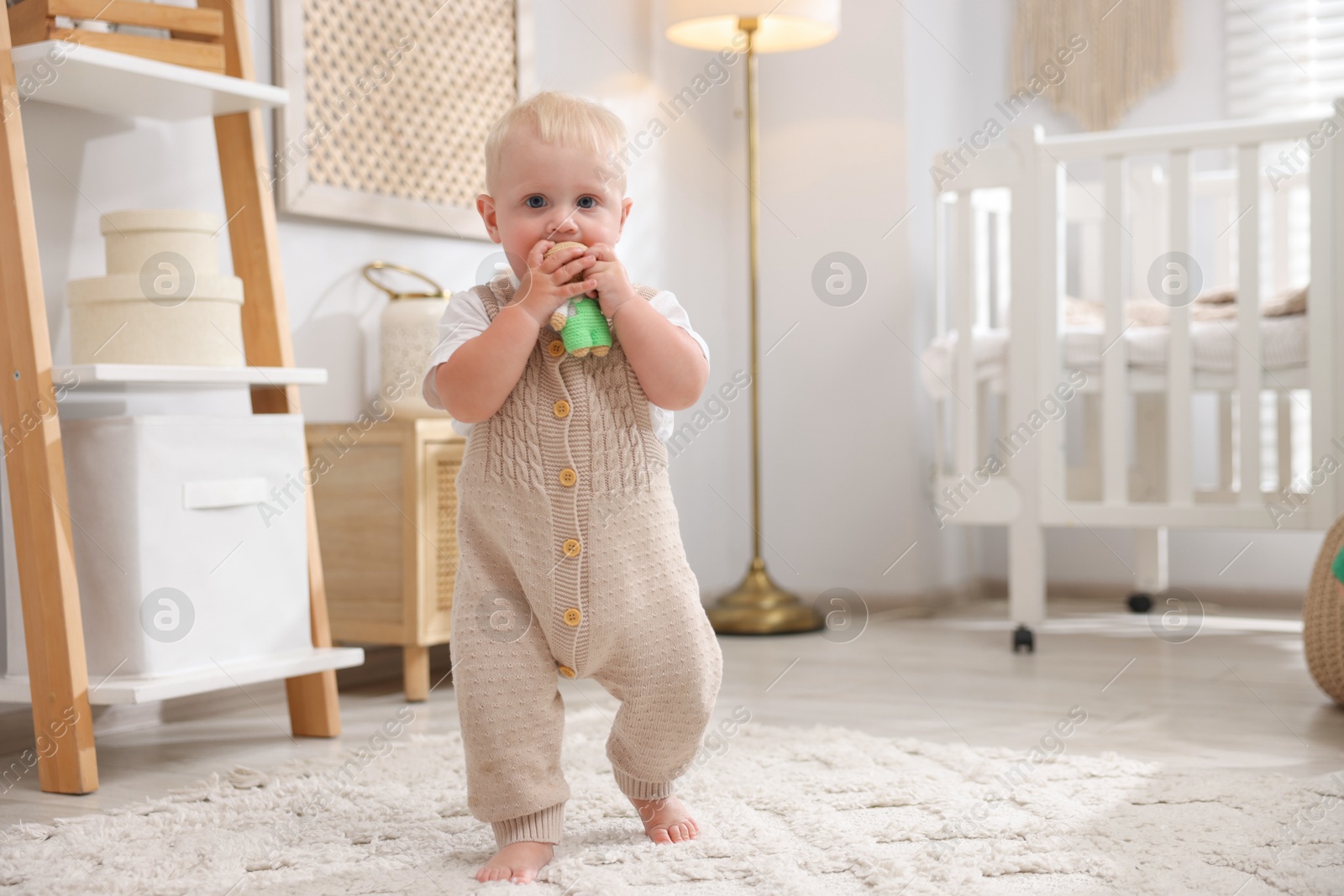 Photo of Cute newborn baby playing with toy in light room