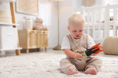 Photo of Cute newborn baby playing with toy in light room. Space for text