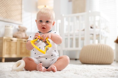 Photo of Cute newborn baby playing with toy tambourine on carpet in light room. Space for text