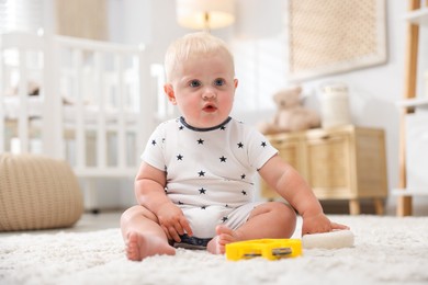 Photo of Cute newborn baby with toys on carpet in light room