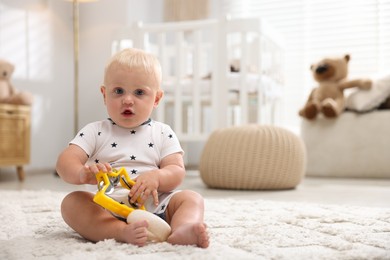 Photo of Cute newborn baby playing with toy tambourine on carpet in light room. Space for text