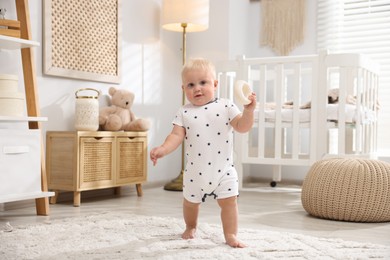 Photo of Cute newborn baby playing with toy in light room