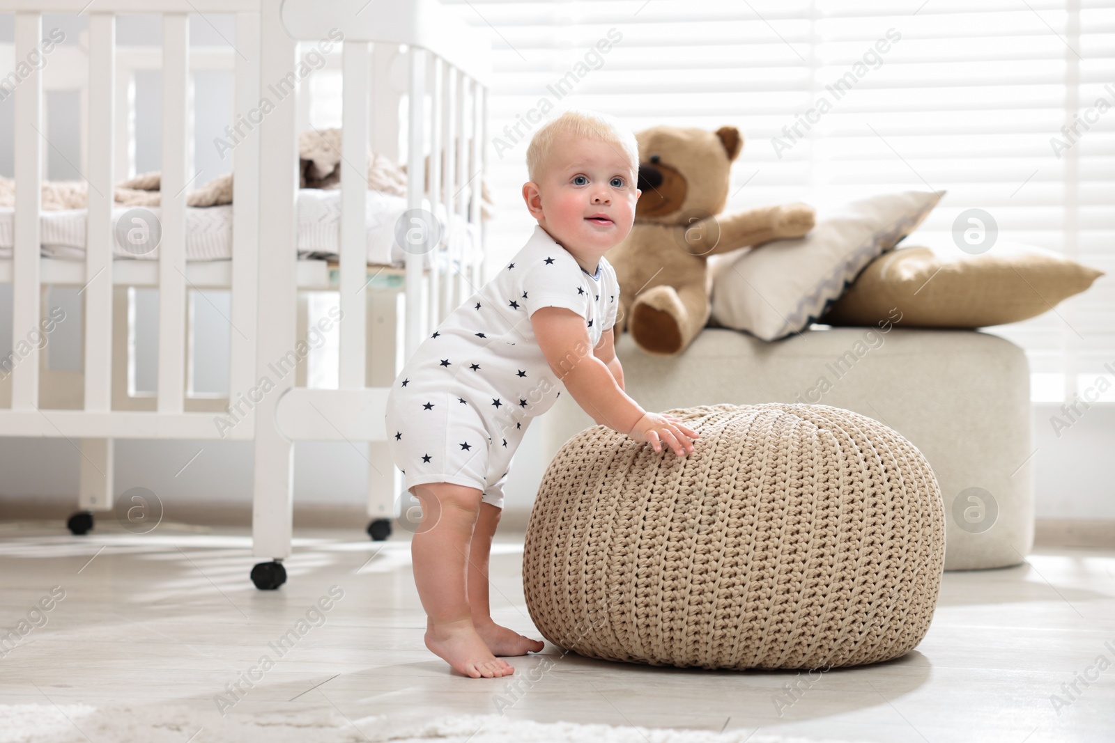 Photo of Cute newborn baby with pouf in light room