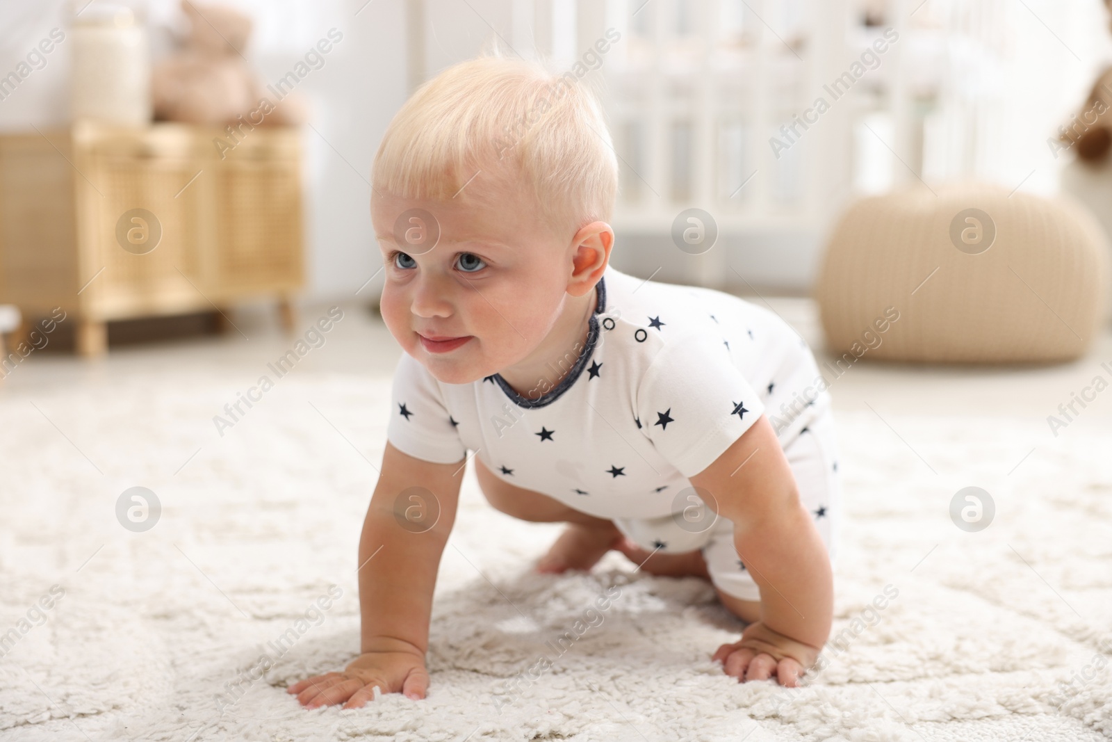 Photo of Cute newborn baby crawling on carpet in light room
