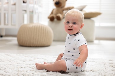 Photo of Cute newborn baby sitting on carpet in light room
