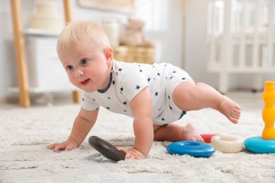 Photo of Cute newborn baby crawling on carpet in light room