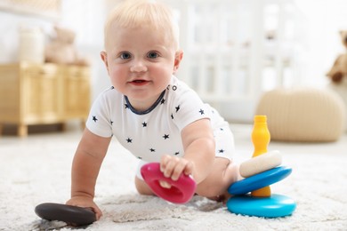 Photo of Cute newborn baby playing with toy on carpet in light room