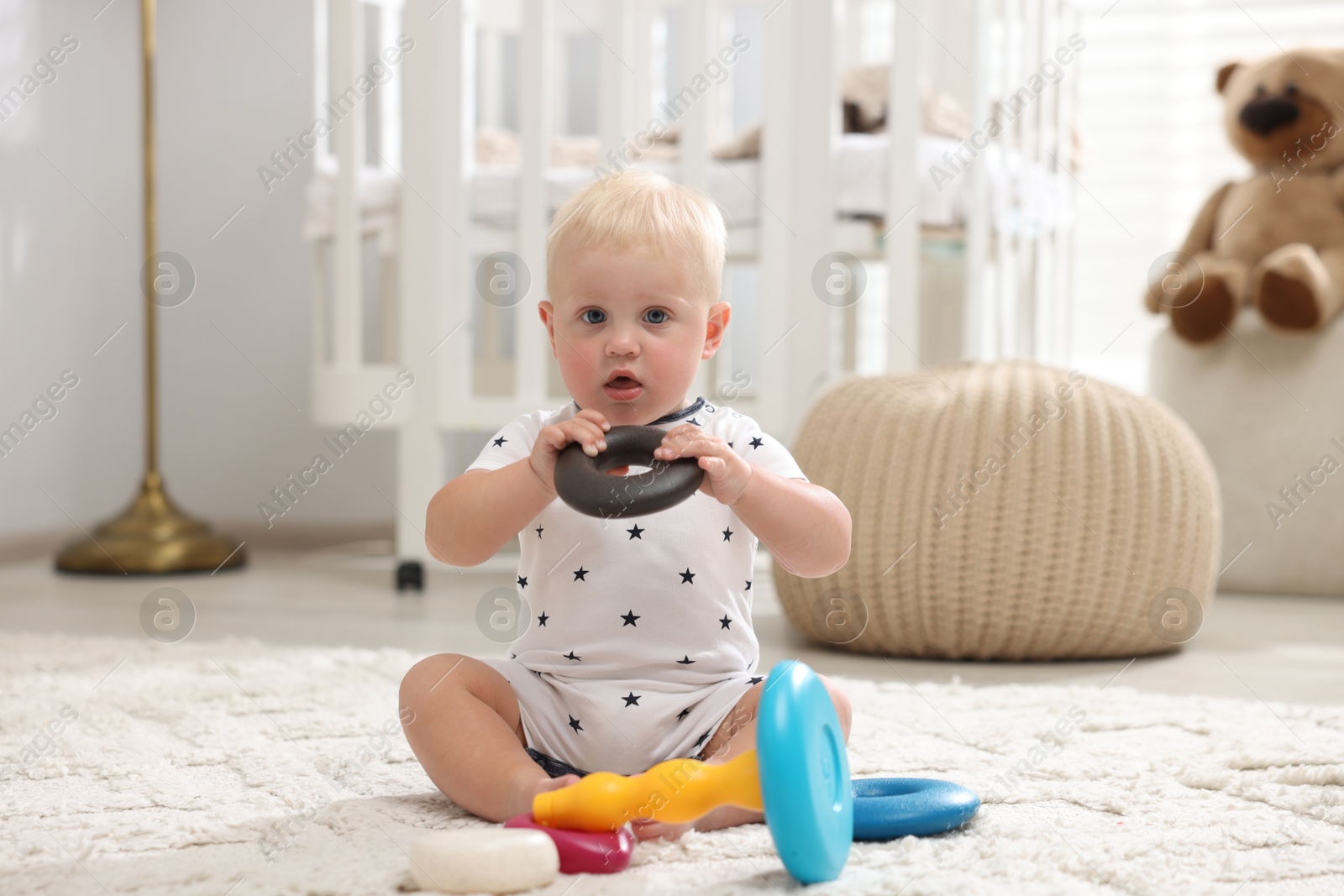 Cute newborn baby playing with toy on carpet in light room Photo of Cute newborn baby playing with toy on carpet in light room