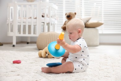 Photo of Cute newborn baby playing with toy on carpet in light room