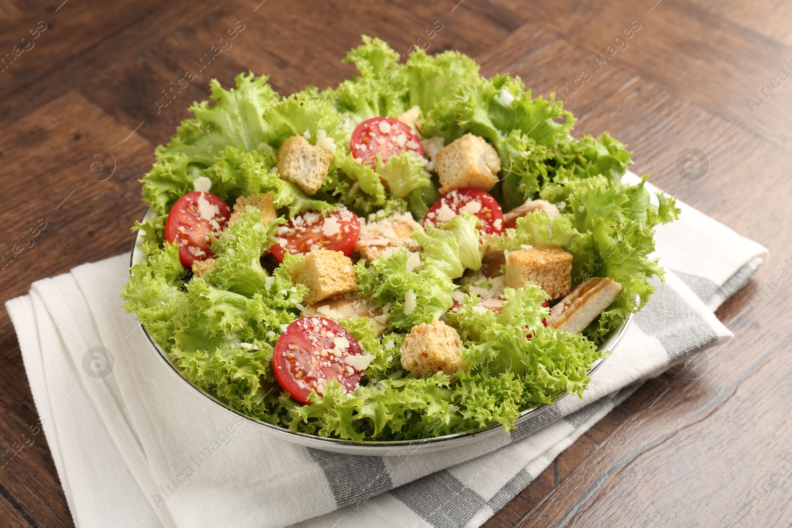 Photo of Tasty salad with croutons, tomatoes, cheese and chicken on wooden table, closeup