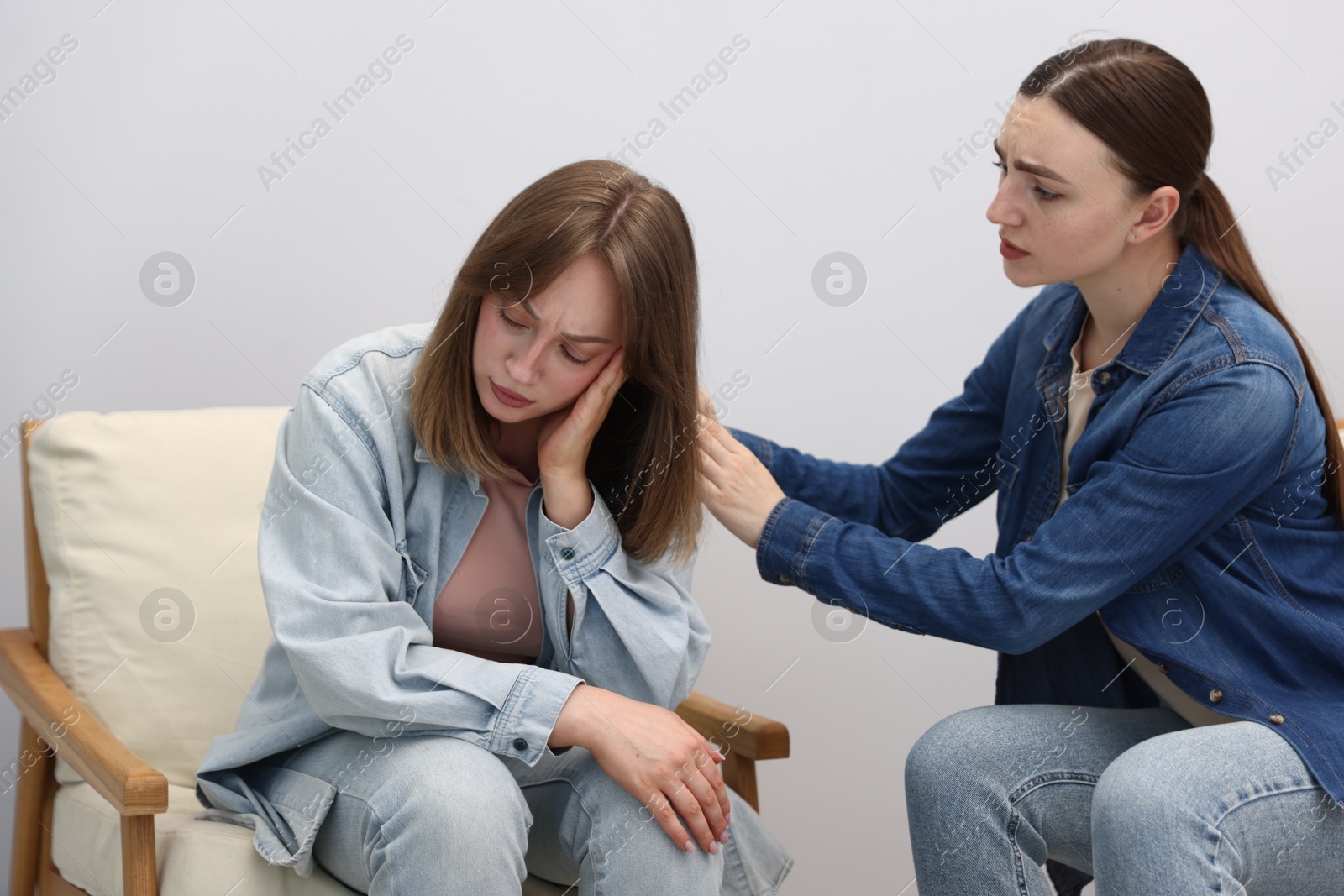 Woman apologizing to her offended friend on armchair near grey wall at home Photo of Woman apologizing to her offended friend on armchair near grey wall at home
