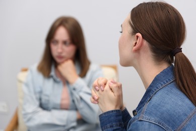 Photo of Woman apologizing to her offended friend on armchair at home, selective focus