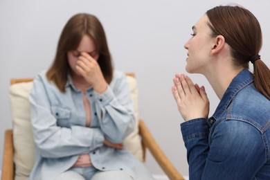 Photo of Woman apologizing to her offended friend on armchair at home, selective focus