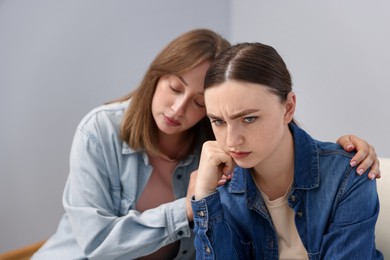 Photo of Woman apologizing to her offended friend near grey wall at home
