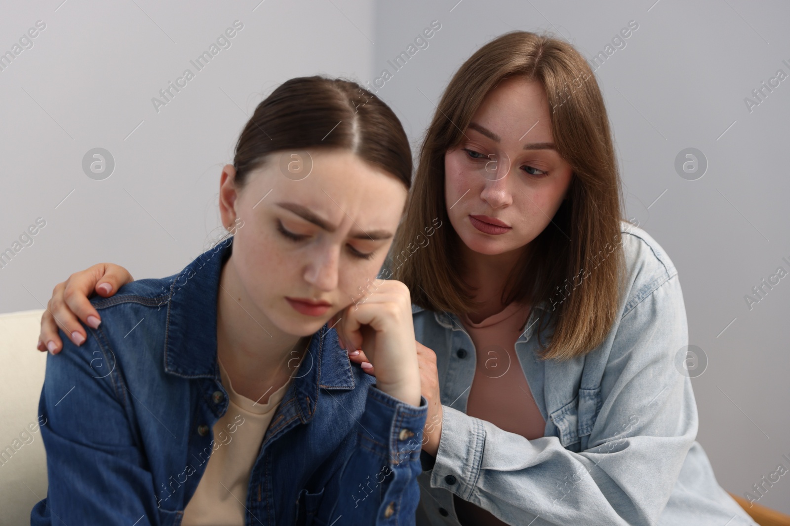 Photo of Woman apologizing to her offended friend near grey wall at home