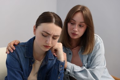 Photo of Woman apologizing to her offended friend near grey wall at home