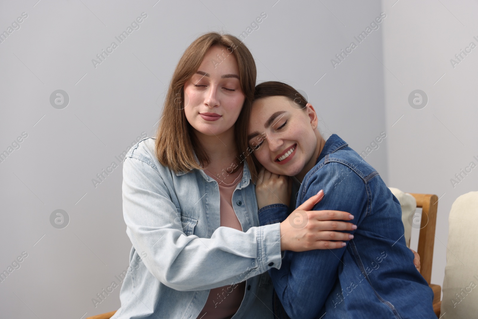 Happy friends after apology near grey wall at home Photo of Happy friends after apology near grey wall at home