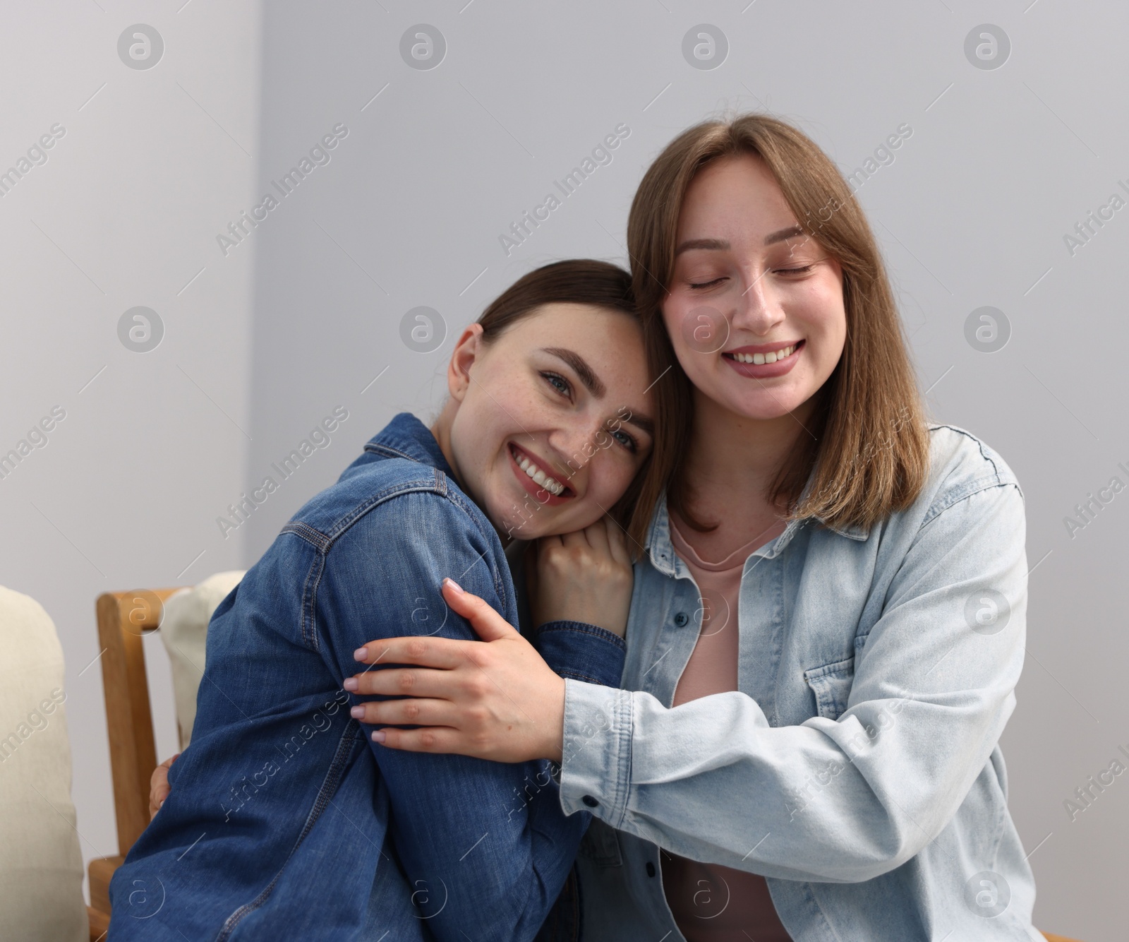 Photo of Happy friends after apology near grey wall at home
