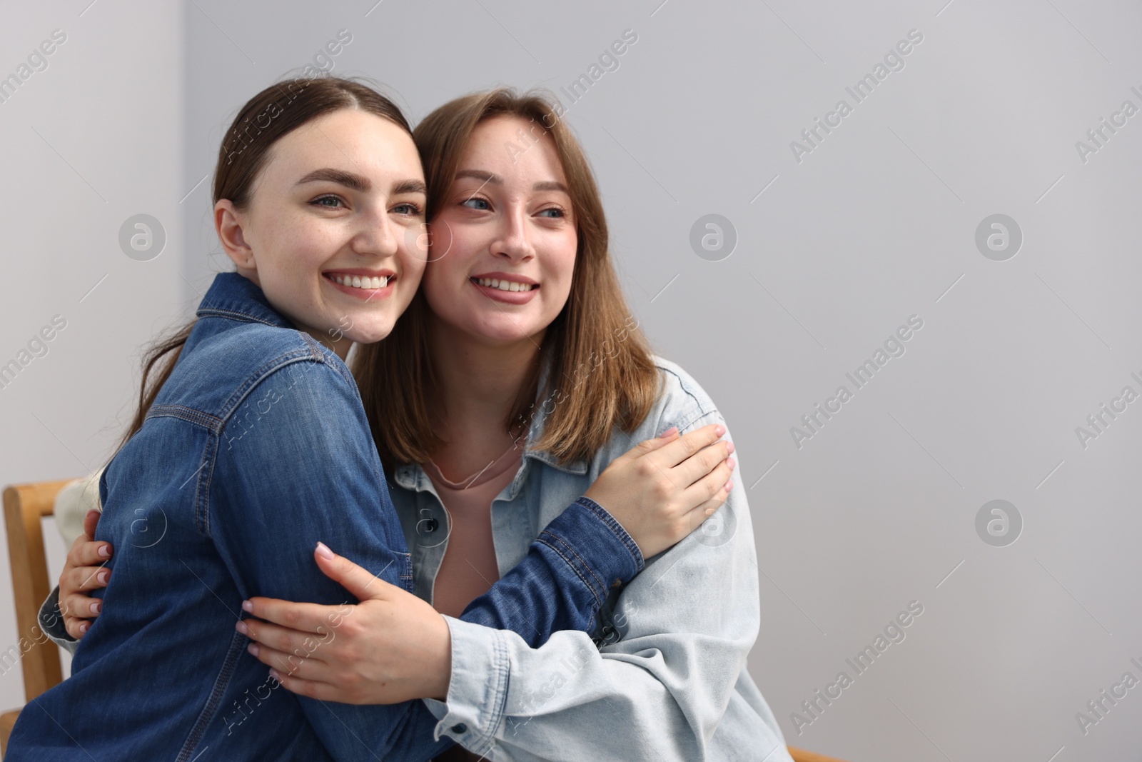 Happy friends after apology near grey wall at home. Space for text Photo of Happy friends after apology near grey wall at home. Space for text