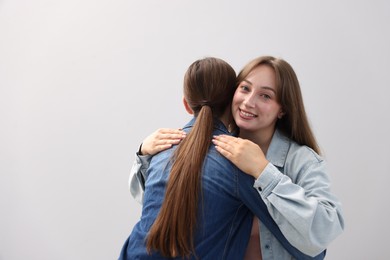Photo of Happy friends hugging after apology on grey background. Space for text
