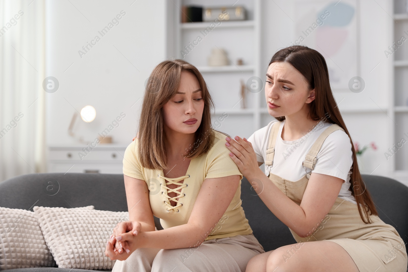 Woman apologizing to her offended friend on sofa at home Photo of Woman apologizing to her offended friend on sofa at home