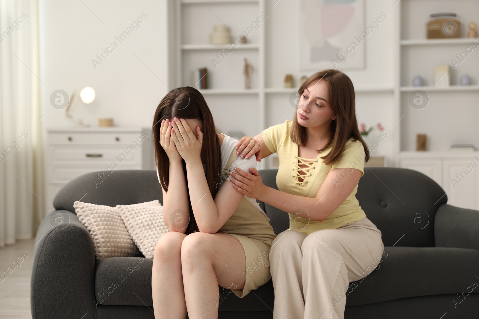 Woman apologizing to her offended friend on sofa at home Photo of Woman apologizing to her offended friend on sofa at home