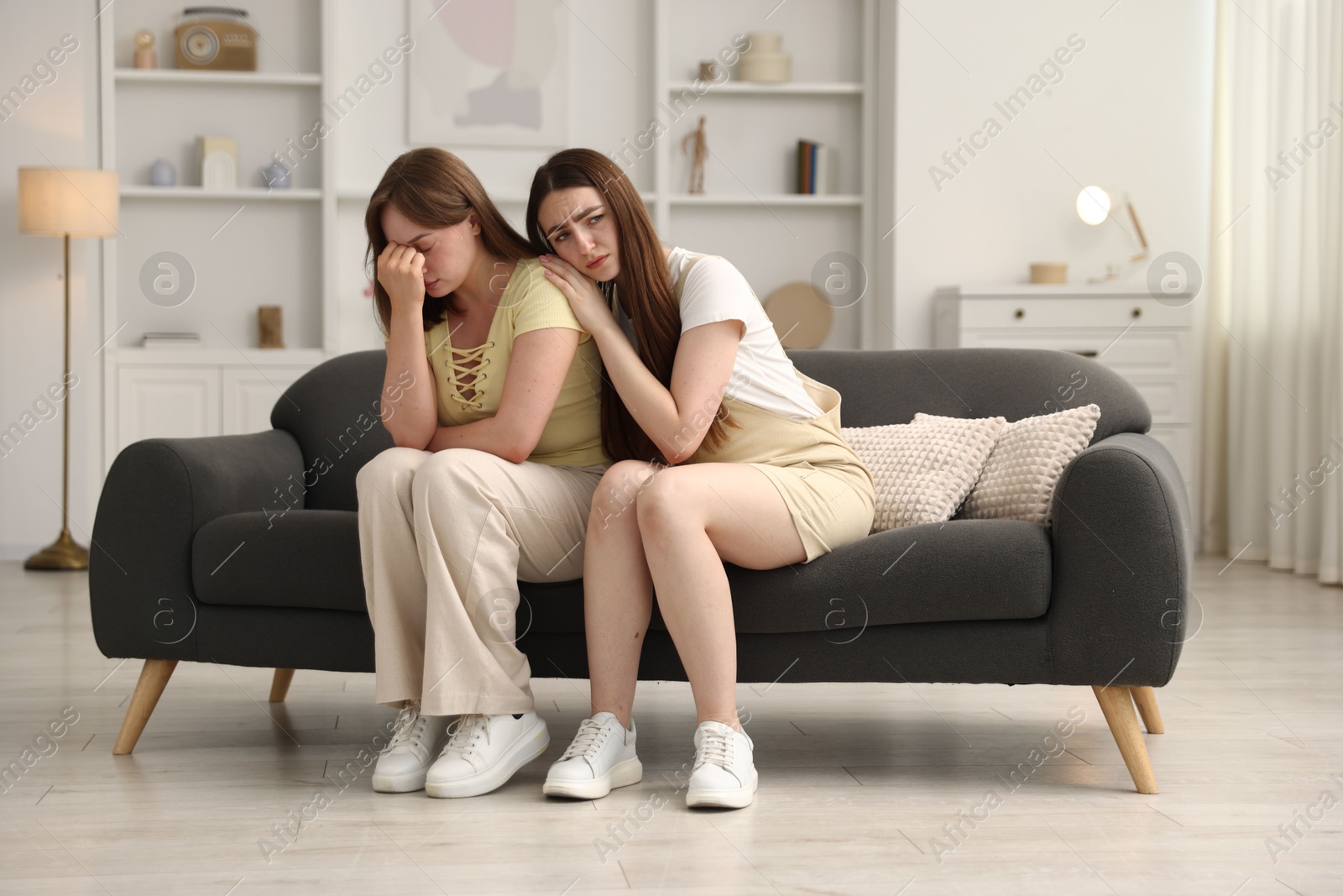 Woman apologizing to her offended friend on sofa at home Photo of Woman apologizing to her offended friend on sofa at home