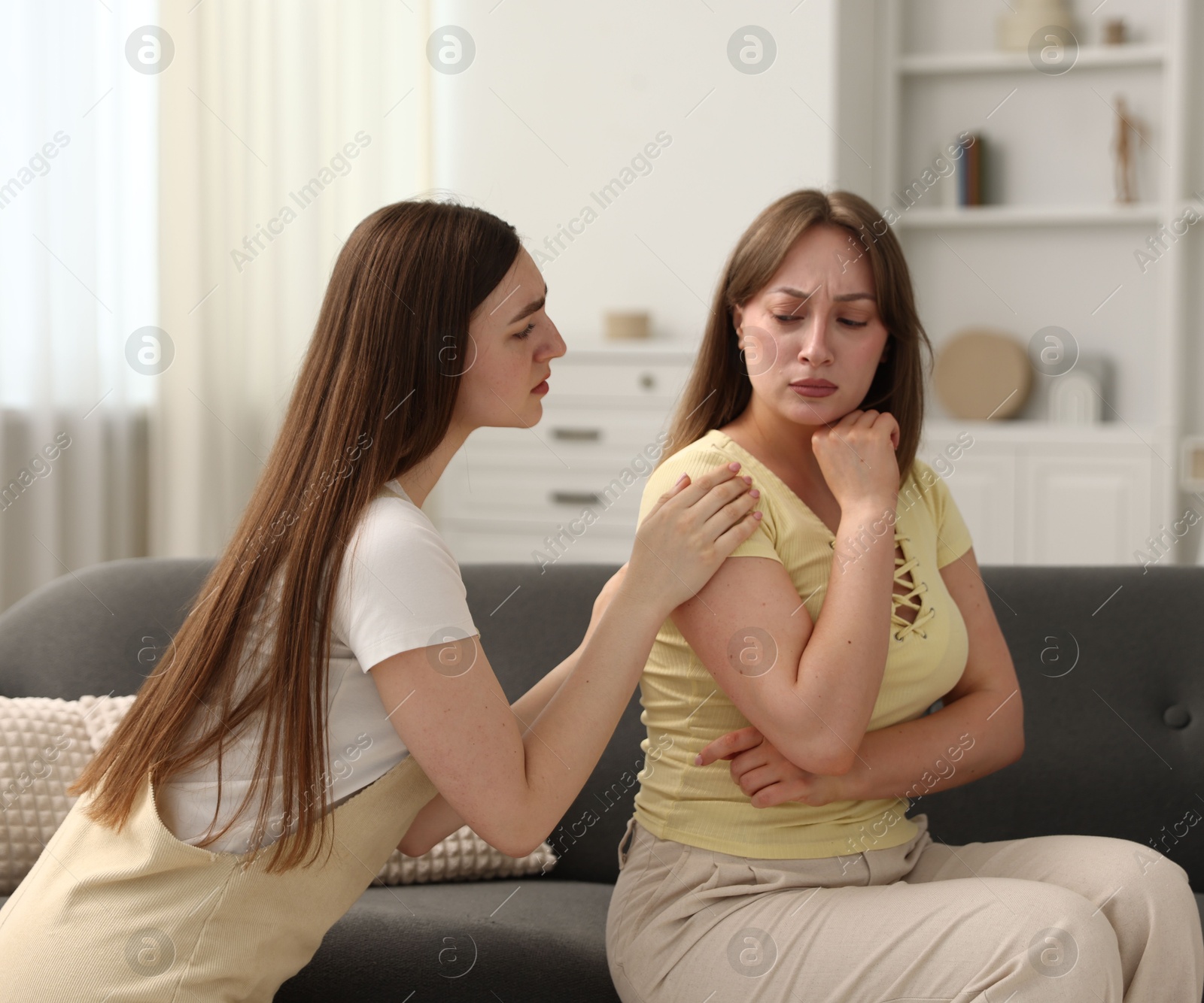 Photo of Woman apologizing to her offended friend on sofa at home