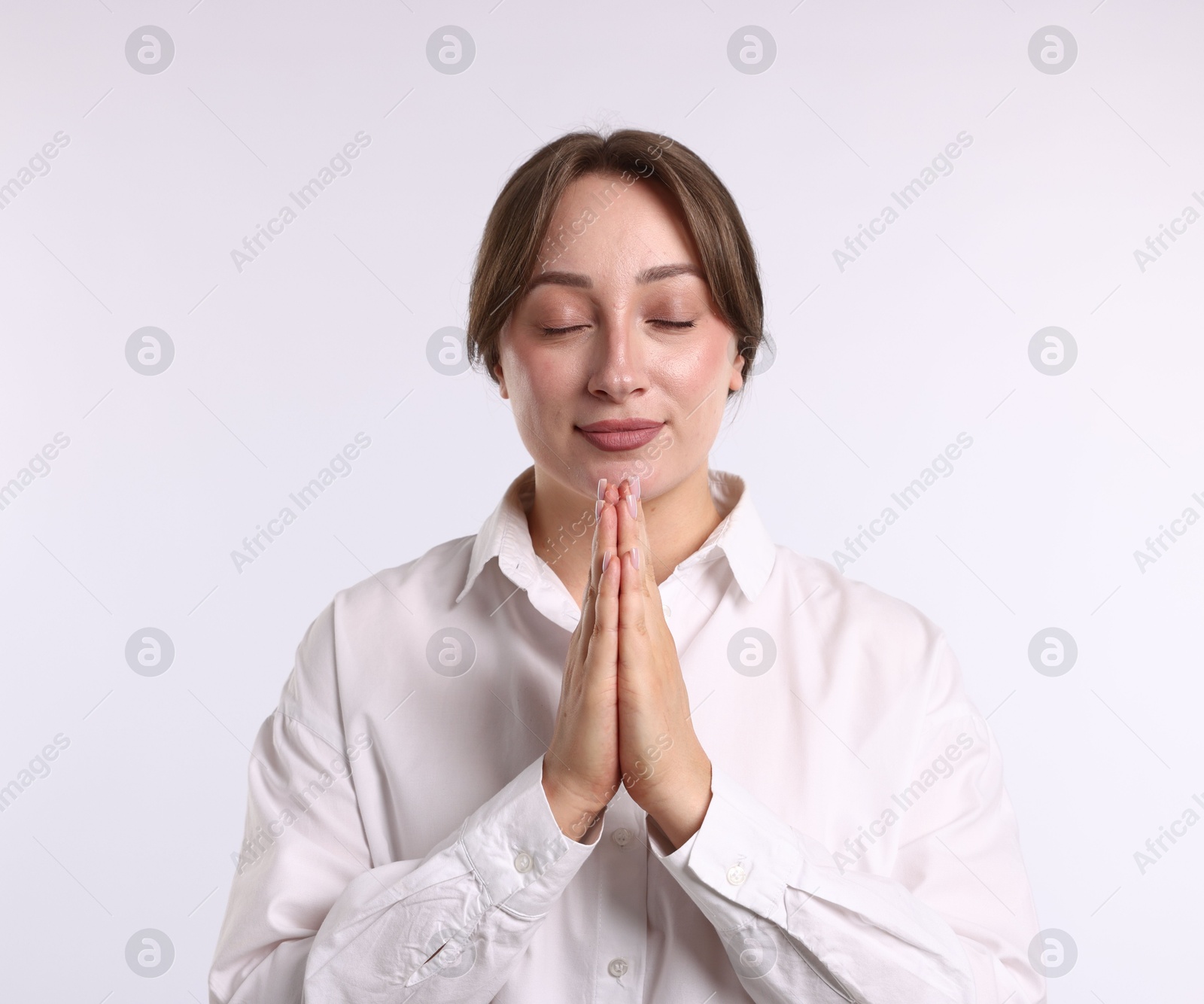 Woman with clasped hands apologizing on white background Photo of Woman with clasped hands apologizing on white background