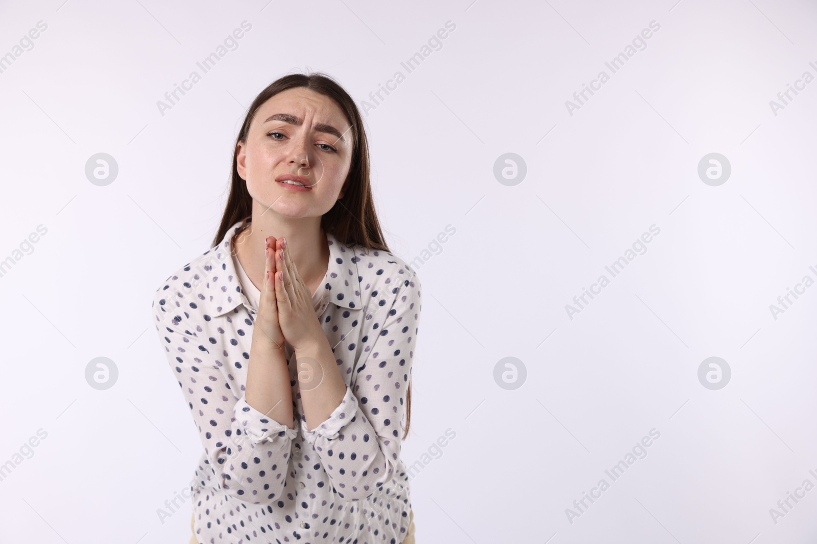 Emotional woman with clasped hands apologizing on white background. Space for text Photo of Emotional woman with clasped hands apologizing on white background. Space for text