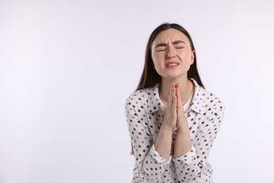 Photo of Emotional woman with clasped hands apologizing on white background. Space for text