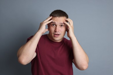 Photo of Man suffering from panic attack on grey background