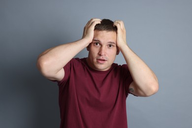 Photo of Man suffering from panic attack on grey background