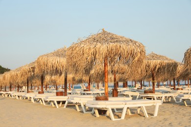 Photo of Beautiful straw umbrellas and sunbeds on sandy beach