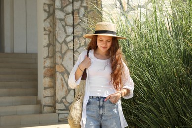 Photo of Beautiful girl in straw hat and bag outdoors on sunny day