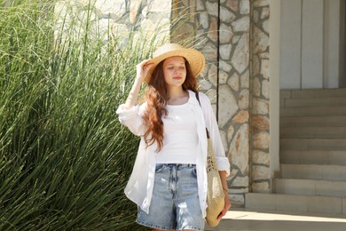 Photo of Beautiful girl in straw hat and bag outdoors on sunny day