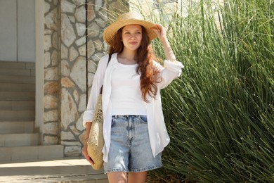 Photo of Beautiful girl in straw hat and bag outdoors on sunny day