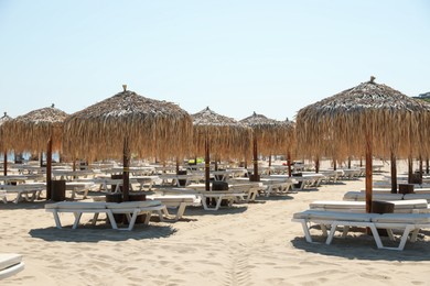 Photo of Beautiful straw umbrellas and sunbeds on sandy beach