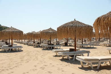 Photo of Beautiful straw umbrellas and sunbeds on sandy beach