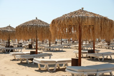 Photo of Beautiful straw umbrellas and sunbeds on sandy beach