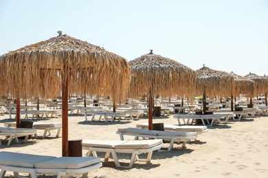 Photo of Beautiful straw umbrellas and sunbeds on sandy beach