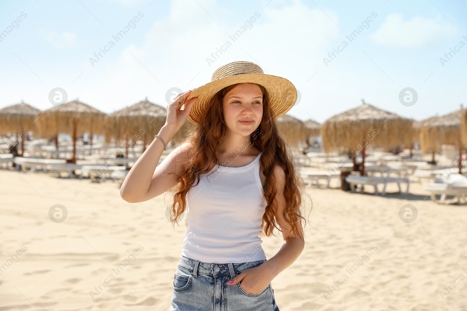 Beautiful girl in straw hat on sandy beach Photo of Beautiful girl in straw hat on sandy beach