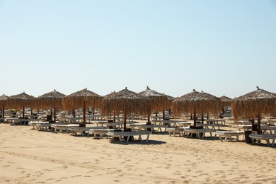 Photo of Beautiful straw umbrellas and sunbeds on sandy beach